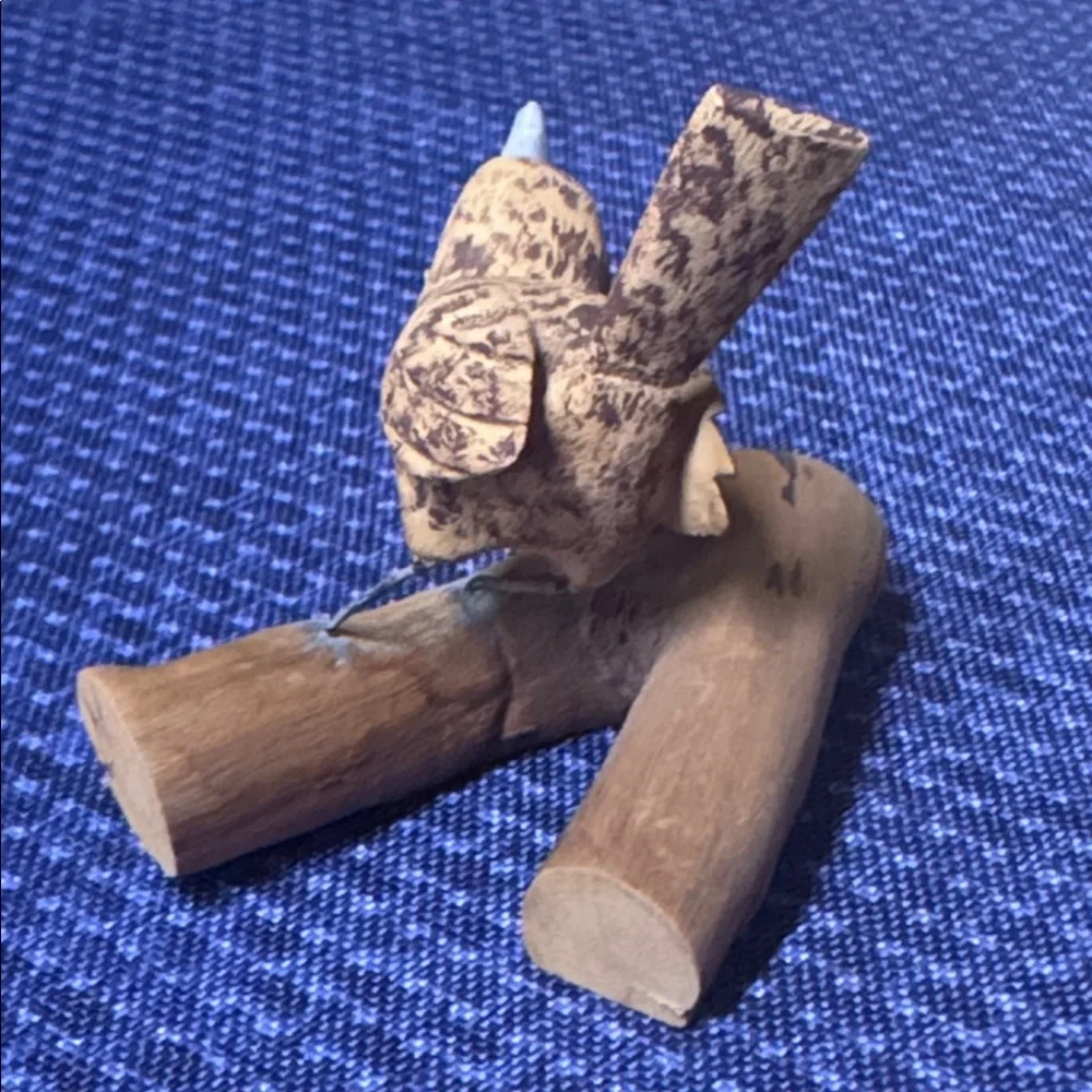 Hand carved wooden bird sculpture perched on a piece of natural wood signed